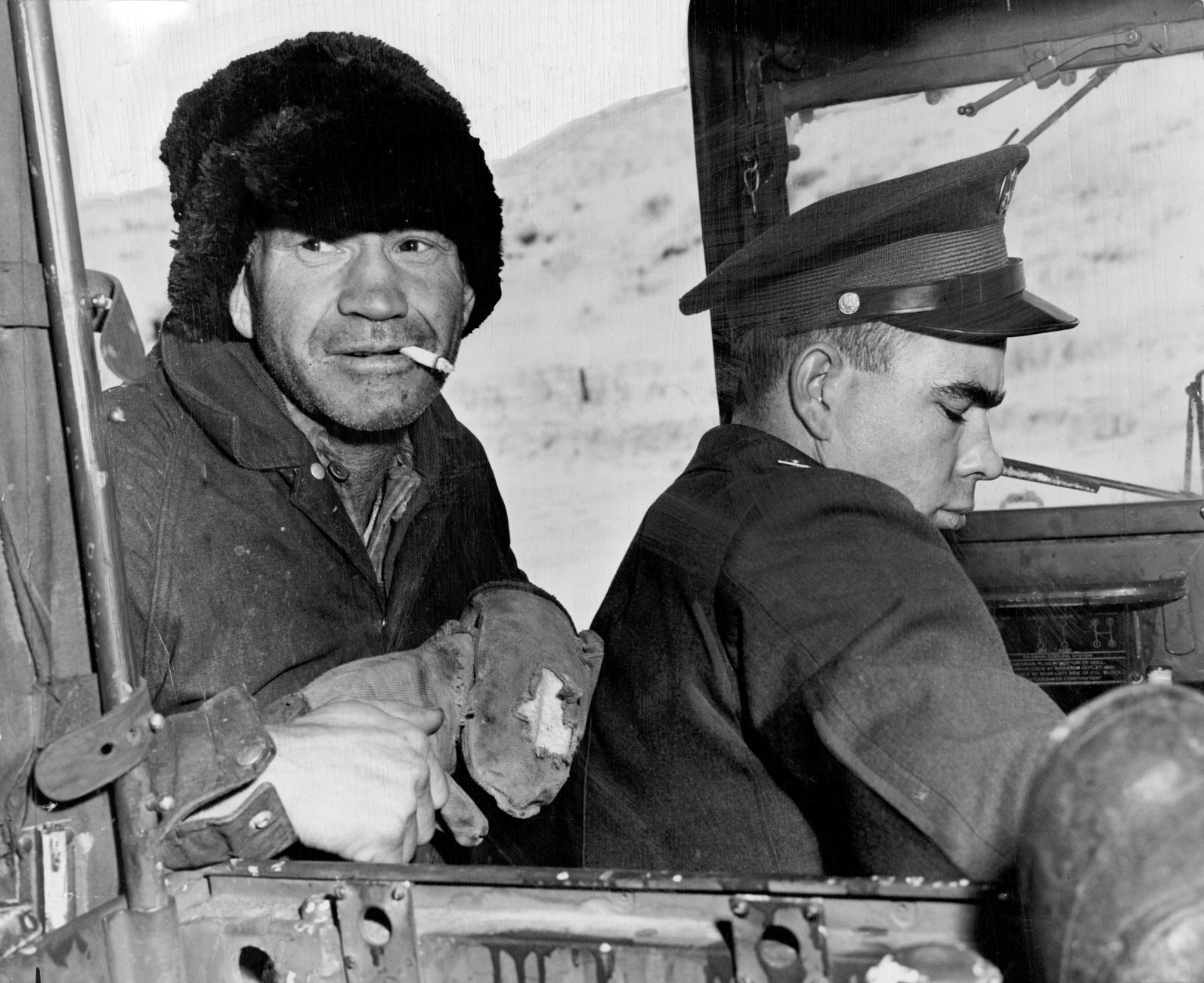 Frank Finley, left, a farmer along the weasel's mercy route, pokes his head in to study the strange vehicle. Soldier at right is Pfc. M.E. (Buck) Hardwick of Camp Carson, Colo. Published Feb. 6, 1949.